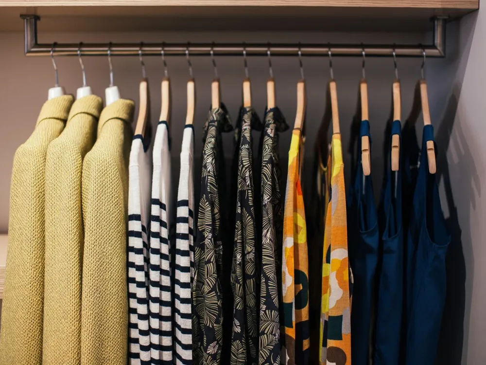 Clothes neatly hung on rails in an organized closet, the kind of organizing a seasonal wardrobe swap involves
