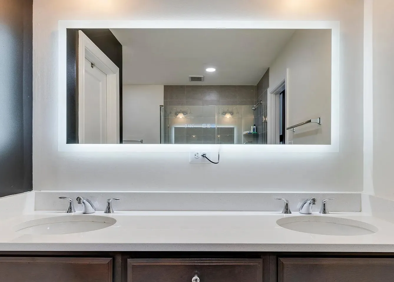 Freshly cleaned double bathroom vanity with a backlit mirror after a cleaning by TCS Cleaning Service