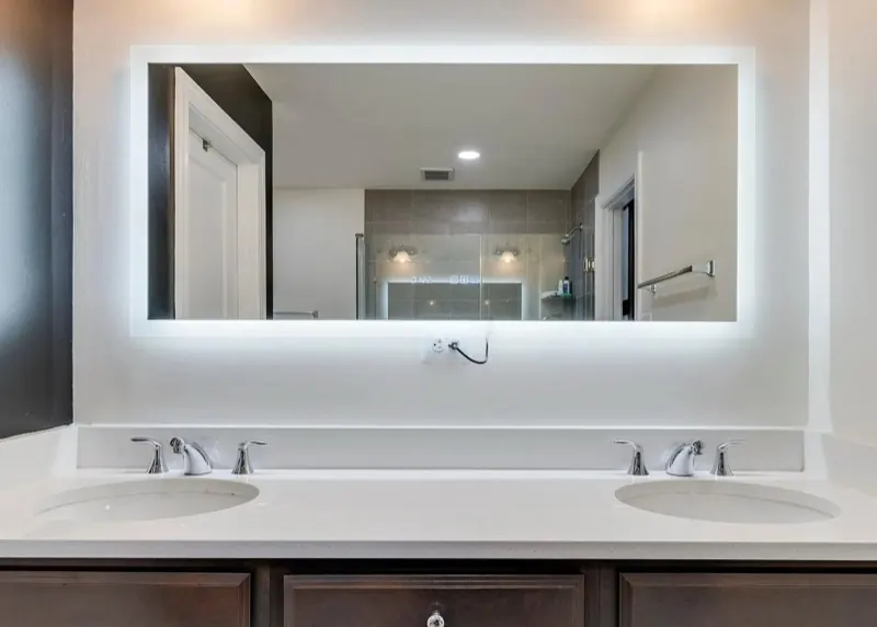 Freshly cleaned double bathroom vanity with a backlit mirror, the kind of restroom detail a workplace needs kept clean