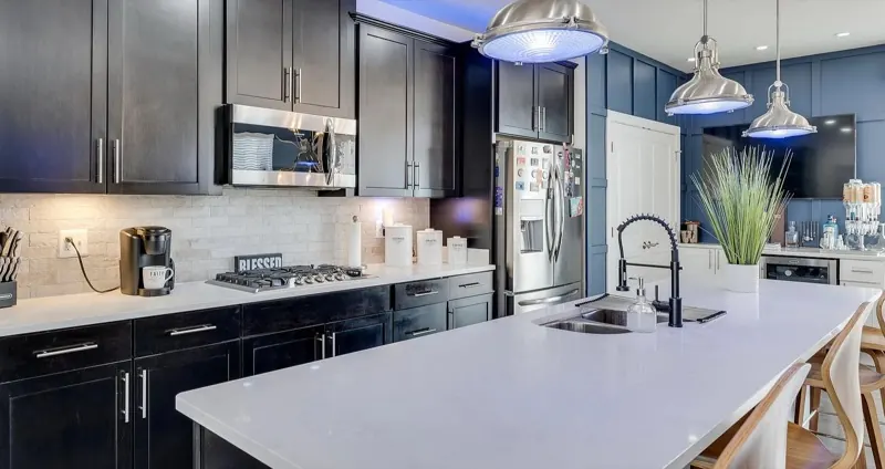 Kitchen with dark cabinets, white island and pendant lights after cleaning (Deep Cleaning by TCS Cleaning Service)