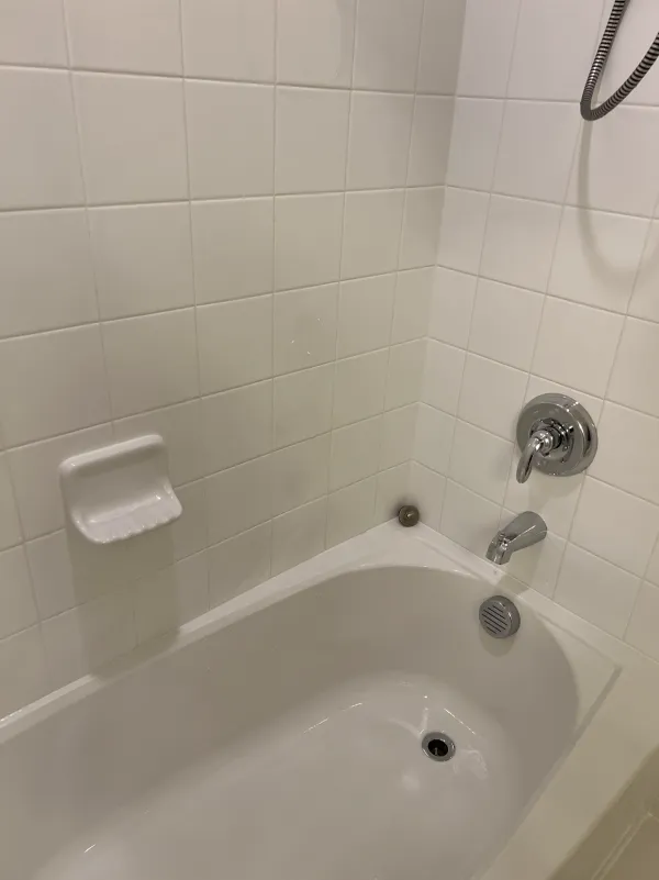 Clean white bathtub with white wall tile and polished chrome fixtures (House Cleaning by TCS Cleaning Service)