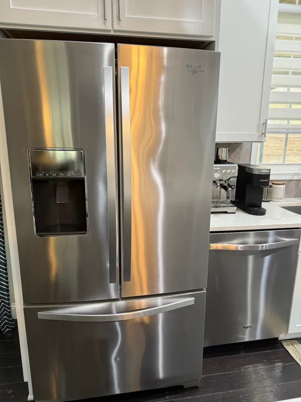 Streak-free stainless steel refrigerator and dishwasher in a white kitchen (House Cleaning by TCS Cleaning Service)