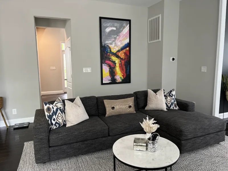 Living room with a dark gray sectional, a marble coffee table and a woven rug (House Cleaning by TCS Cleaning Service)