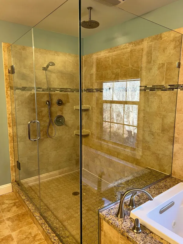Glass-enclosed shower with beige tile next to a white soaking tub (House Cleaning by TCS Cleaning Service)