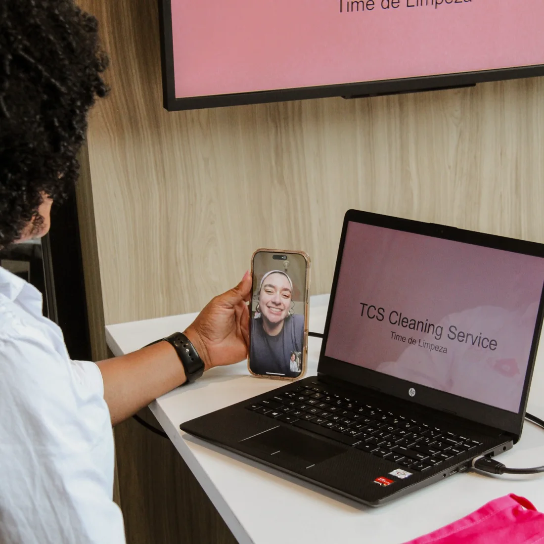 TCS Cleaning Service team video call: a phone showing a smiling team member next to a laptop with the company name