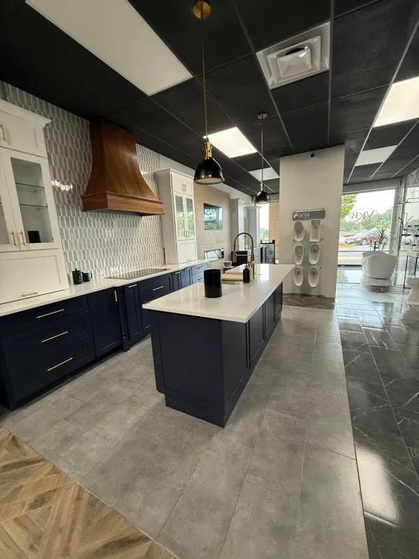 Kitchen showroom with navy cabinets, a white island and polished tile floors