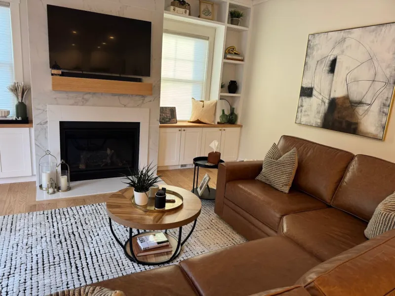 Living room with a leather sectional, a marble fireplace and a tidy coffee table