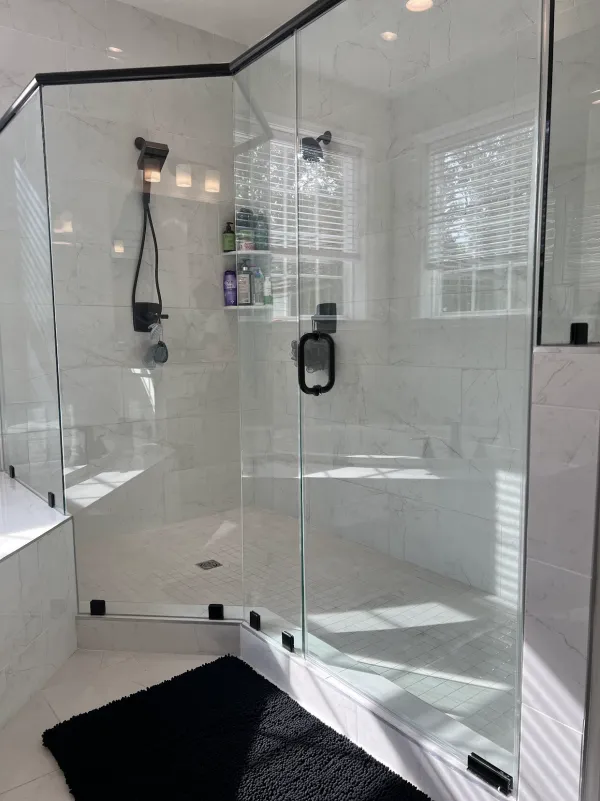 Walk-in shower with clear glass panels and white marble-look tile